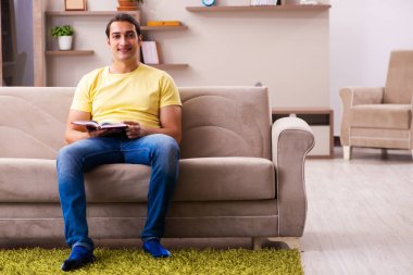 Evde kitap okuyan genç bir erkek öğrenci.