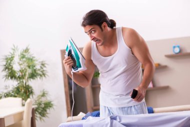 Genç erkek çalışan sabah ütü yapıyor.