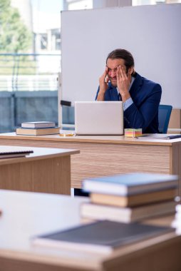 Sınıfta takım elbiseli genç bir erkek öğretmen var.