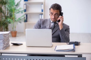 Genç erkek çalışan ofiste telefonla konuşuyor.