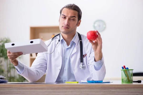 Joven médico dietista sosteniendo caja de manzana y pizza — Foto de Stock