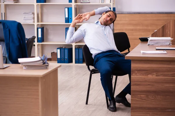 Junge männliche Mitarbeiter dehnen sich am Arbeitsplatz — Stockfoto