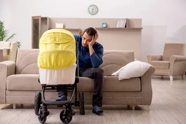 Young male contractor looking after baby at home — Stock Photo, Image