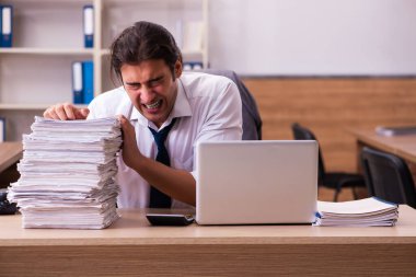 Ofisteki aşırı işten memnun olmayan genç bir erkek işçi.