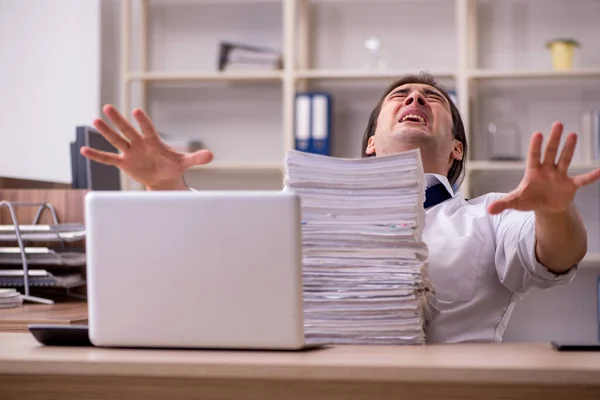 Young male employee unhappy with excessive work in the office — Stock Photo, Image