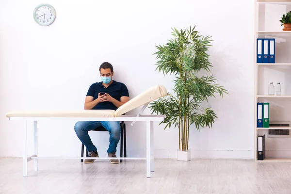 Junger Mann wartet während Pandemie im Krankenhaus auf Arzt — Stockfoto