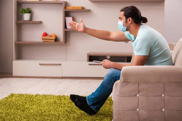 Giovane uomo guardando la tv a casa durante la pandemia — Foto Stock