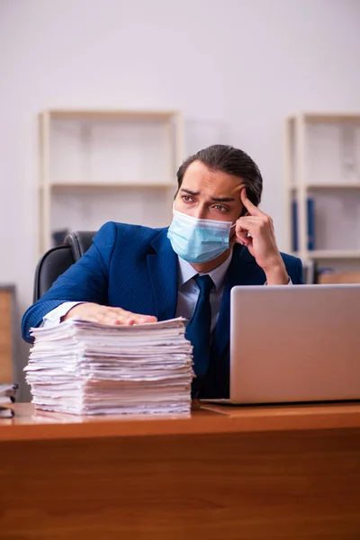 Jovem funcionário do sexo masculino que trabalha no escritório usando máscara — Fotografia de Stock