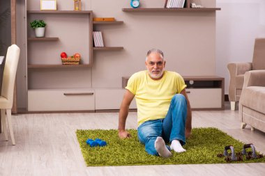 Yaşlı adam evde spor egzersizleri yapıyor.