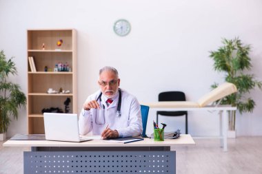 Klinikte çalışan yaşlı erkek doktor.