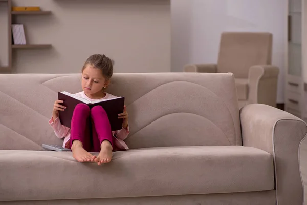 Evde kitap okuyan küçük bir kız. — Stok fotoğraf