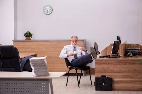 Oude mannelijke werknemer ontbijten op kantoor — Stockfoto