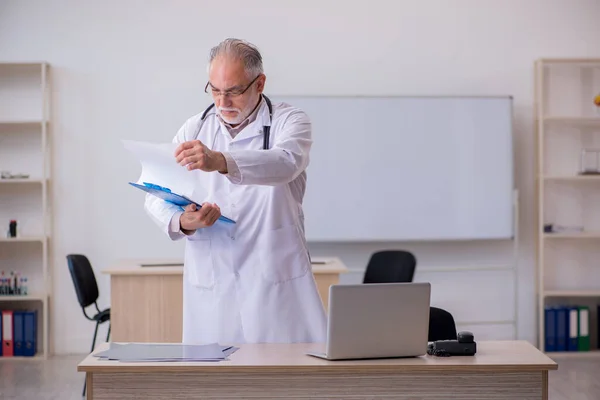 Starý lékař pracující na klinice — Stock fotografie