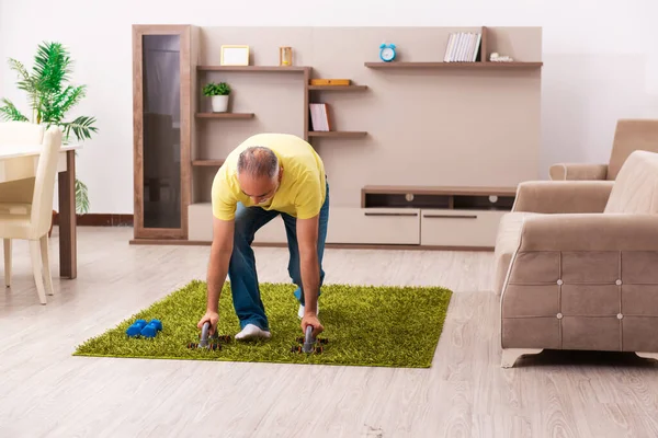 Verouderde man doet sport oefeningen thuis — Stockfoto