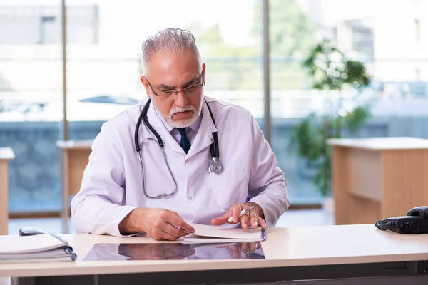 Stary lekarz robi notatki w klinice. — Zdjęcie stockowe