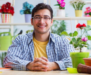 Çiçekçide çalışan genç bir adam.