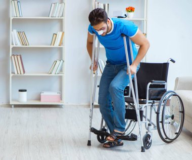 Genç adam ameliyattan sonra koltuk değnekleriyle evde iyileşiyor.