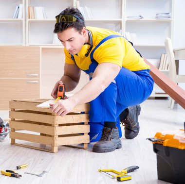 Tamirci marangoz tahta ve ölçü tahtasıyla çalışıyor.