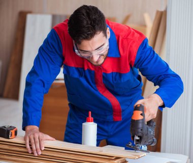 Elektrikli testereyle çalışan genç tamirci.