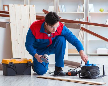 Genç marangoz ahşap kalaslarla çalışıyor.