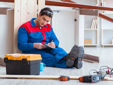 İnşaatta defter planlama yapan genç bir marangoz.