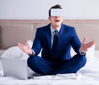 Yatak odasında sanal gerçeklik kulaklığı takan bir iş adamı.