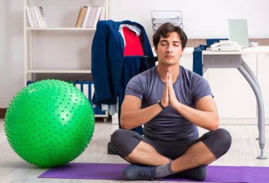 Ofiste egzersiz yapan genç bir erkek.