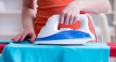 Kadın karısı evde ütü yapıyor.