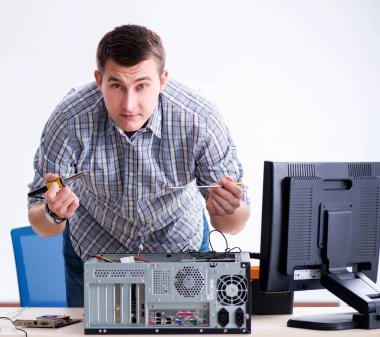 Genç teknisyen atölyede bilgisayar tamir ediyor.