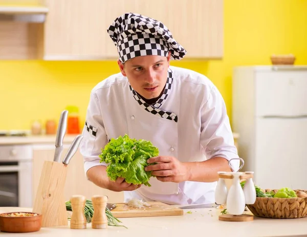 Joven cocinero profesional preparando ensalada en la cocina — Foto de Stock