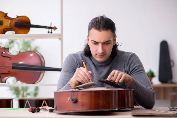 Jonge mannelijke reparateur die cello repareert — Stockfoto