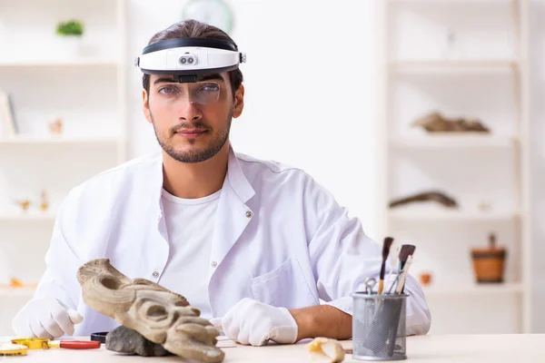 Jonge mannelijke archeoloog bestudeert het oude Afrikaanse steenmasker — Stockfoto