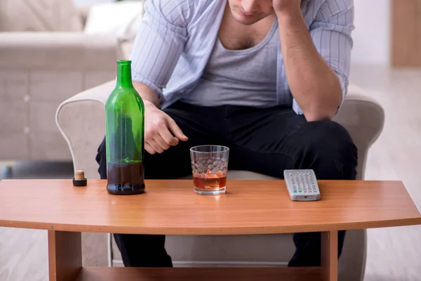Young male alcoholic drinking whiskey at home — Stock Photo, Image