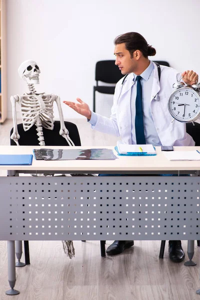 Молодой врач и скелет пациента в управлении временем концепция — стоковое фото