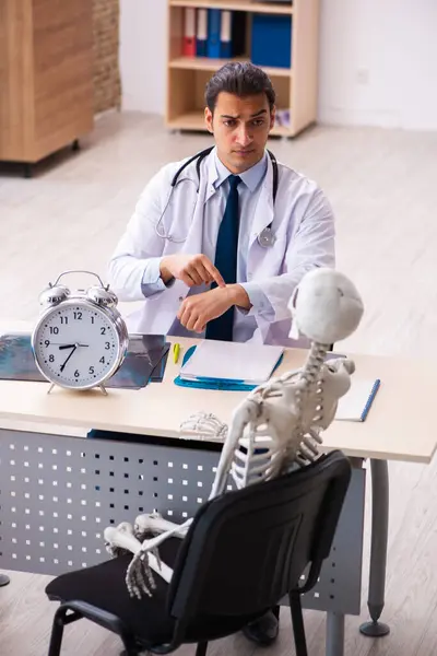 Jonge mannelijke arts en skelet patiënt in time management concep — Stockfoto