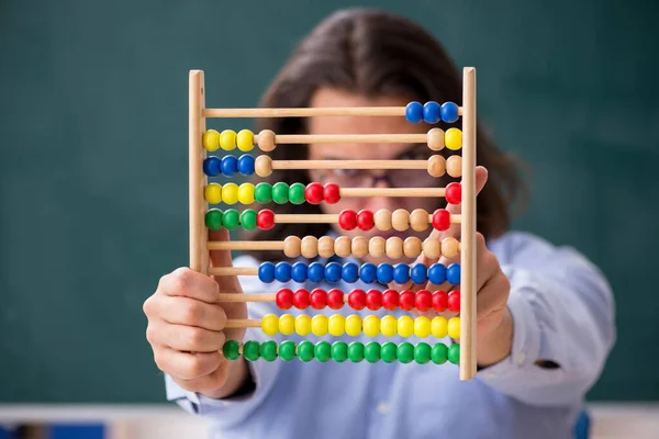 Young male teacher in front of green board