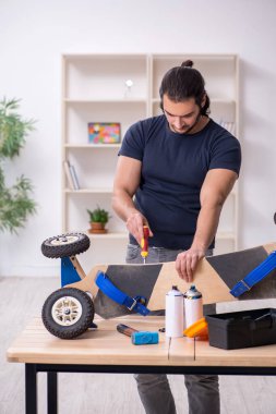 Kaykay tamir eden genç bir erkek tamirci.