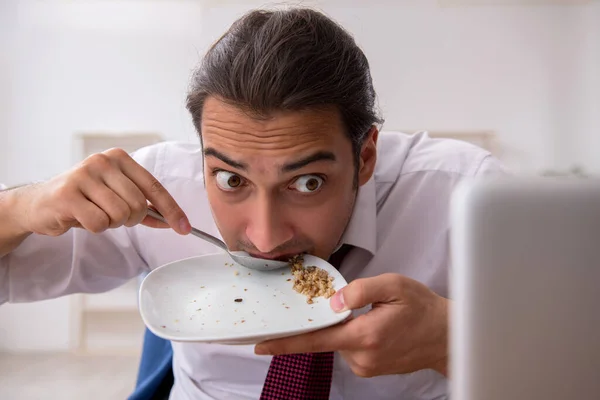 Голодный работник-мужчина ест гречку во время перерыва — стоковое фото