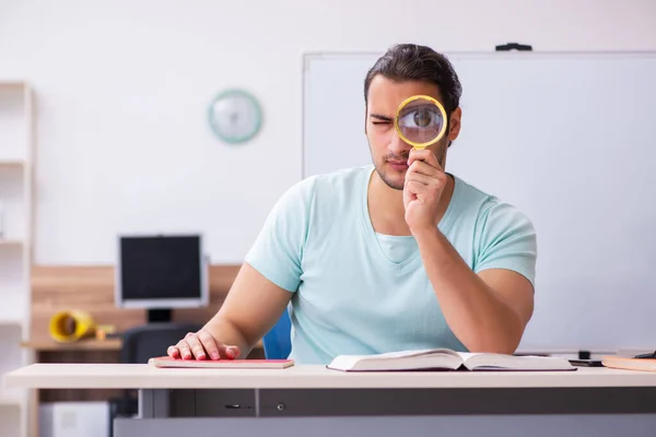 Jeune étudiant masculin se préparant aux examens à la maison tenant loupe — Photo