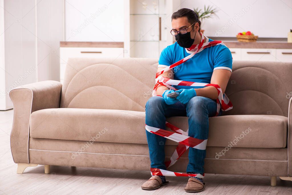Young man watching tv at home in pandemic concept