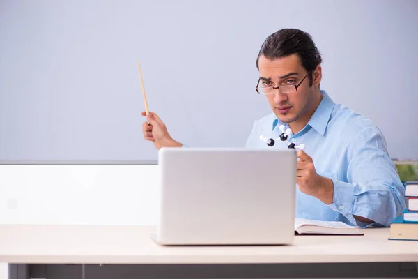 Young male physics teacher in front of whiteboard