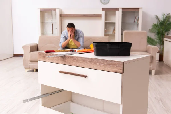 Young male carpenter repairing furniture at home