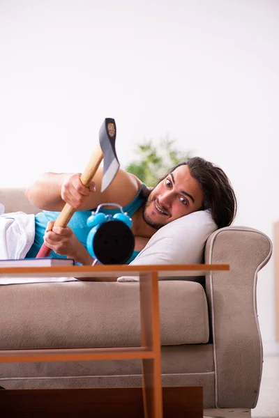 Giovane uomo sdraiato sul divano nel concetto di gestione del tempo — Foto Stock