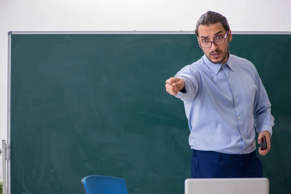 Joven profesor en el aula delante de la mesa verde — Foto de Stock