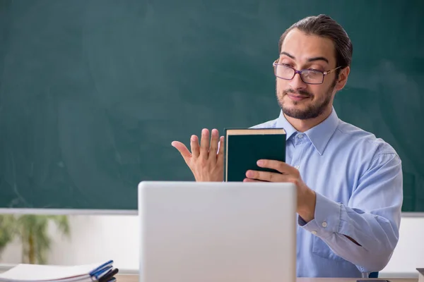 Jonge mannelijke leraar in het klaslokaal in teleonderwijsconcept — Stockfoto