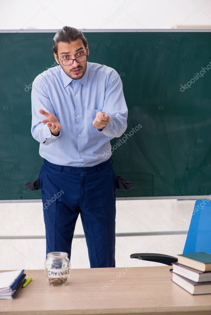 Young underpaid male teacher in the classroom