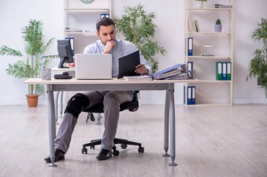 Ofiste çalışan genç bacağı yaralı bir çalışan.