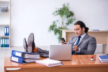 Genç erkek çalışan ofiste kahve içiyor.