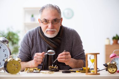 Atölyede çalışan yaşlı bir erkek saatçi.