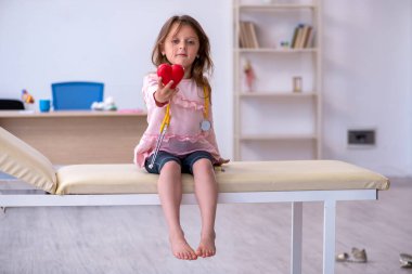 Steteskop tutan küçük bir kız klinikte doktor bekliyor.